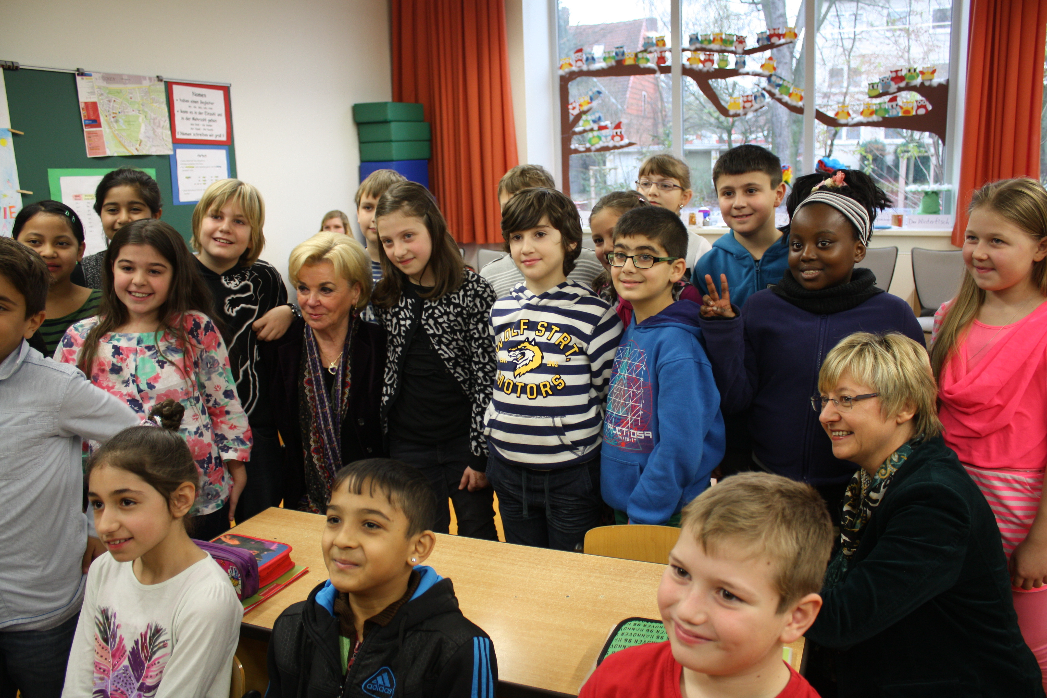 Liz Mohn umgeben von vielen Schülern in einem Klassenraum